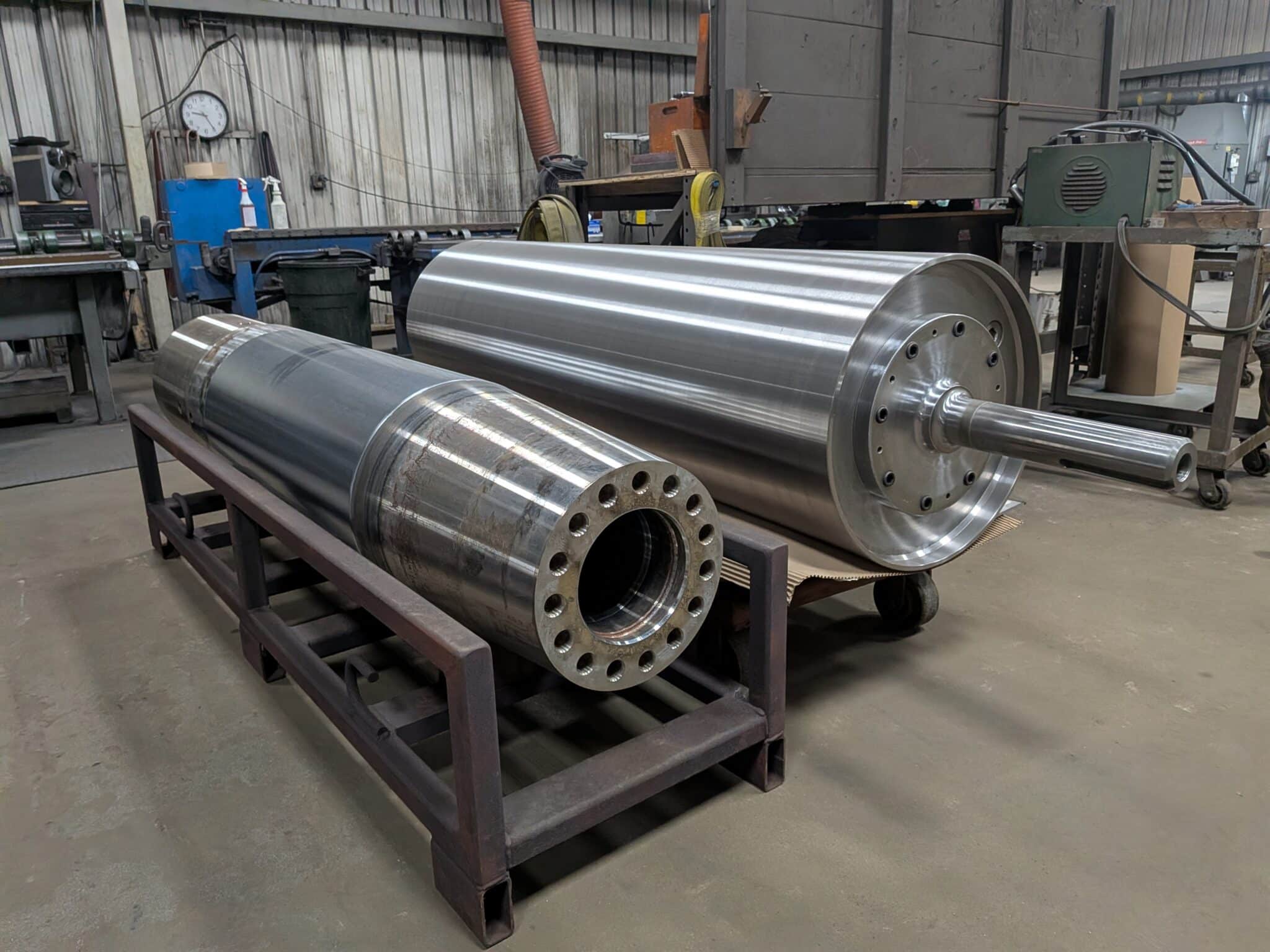 Heavy industrial rolls staged on skids for large-scale vertical hard chrome plating at Pioneer Metal Finishing Chippewa Falls